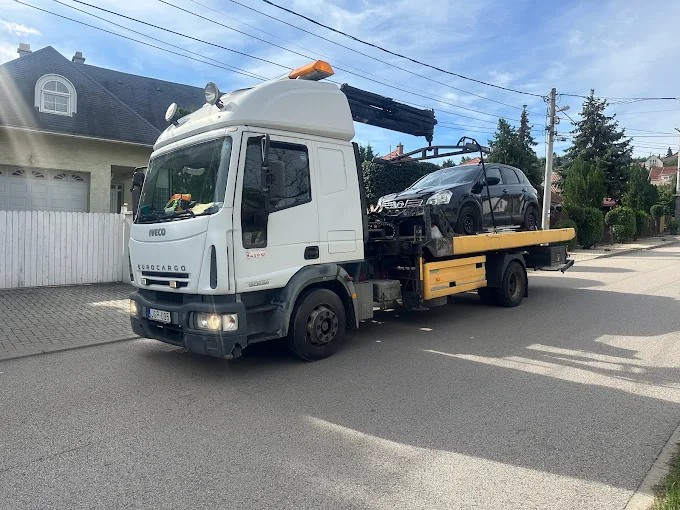IVECO darus autómentő platóján sérült Mitsubishi Outlander, tiszta kék ég
