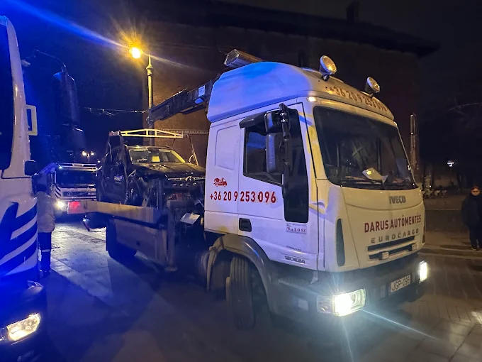 IVECO darus autómentő éjszaka egy budapesti utcán, bekapcsolt munkalámpákkal